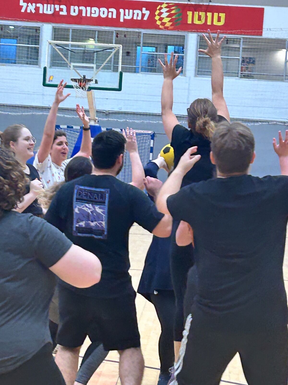 קבוצה מניפה ידיים מול הסל — רגע של חגיגה